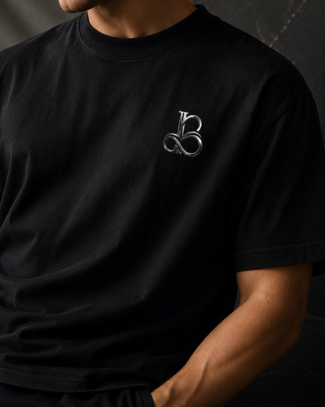 Person wearing a black t-shirt with a logo on the chest against a dark background