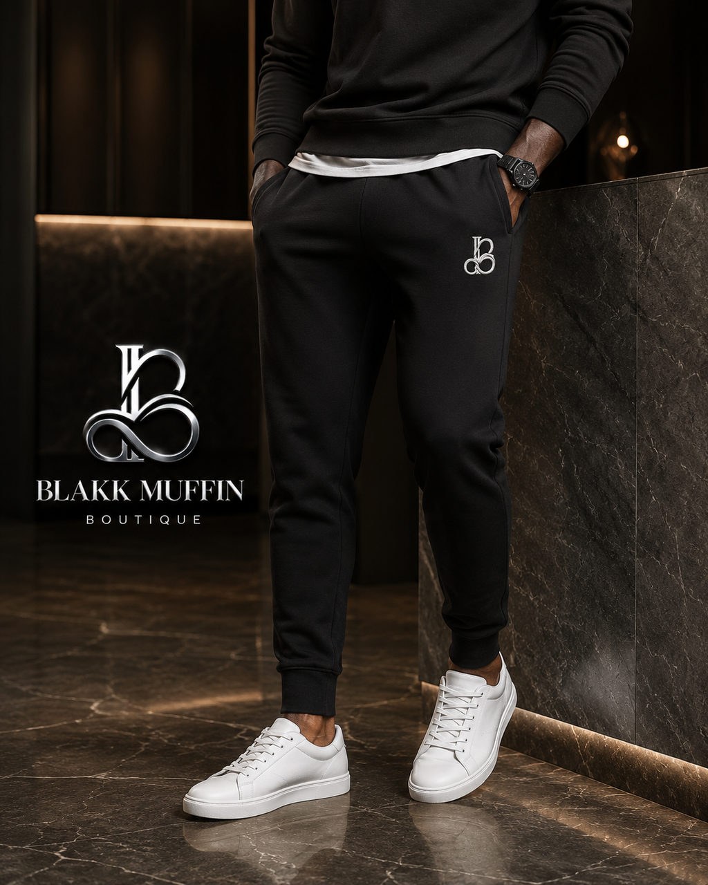 Person wearing black jogger pants and white sneakers with Blakk Muffin Boutique logo in the background.