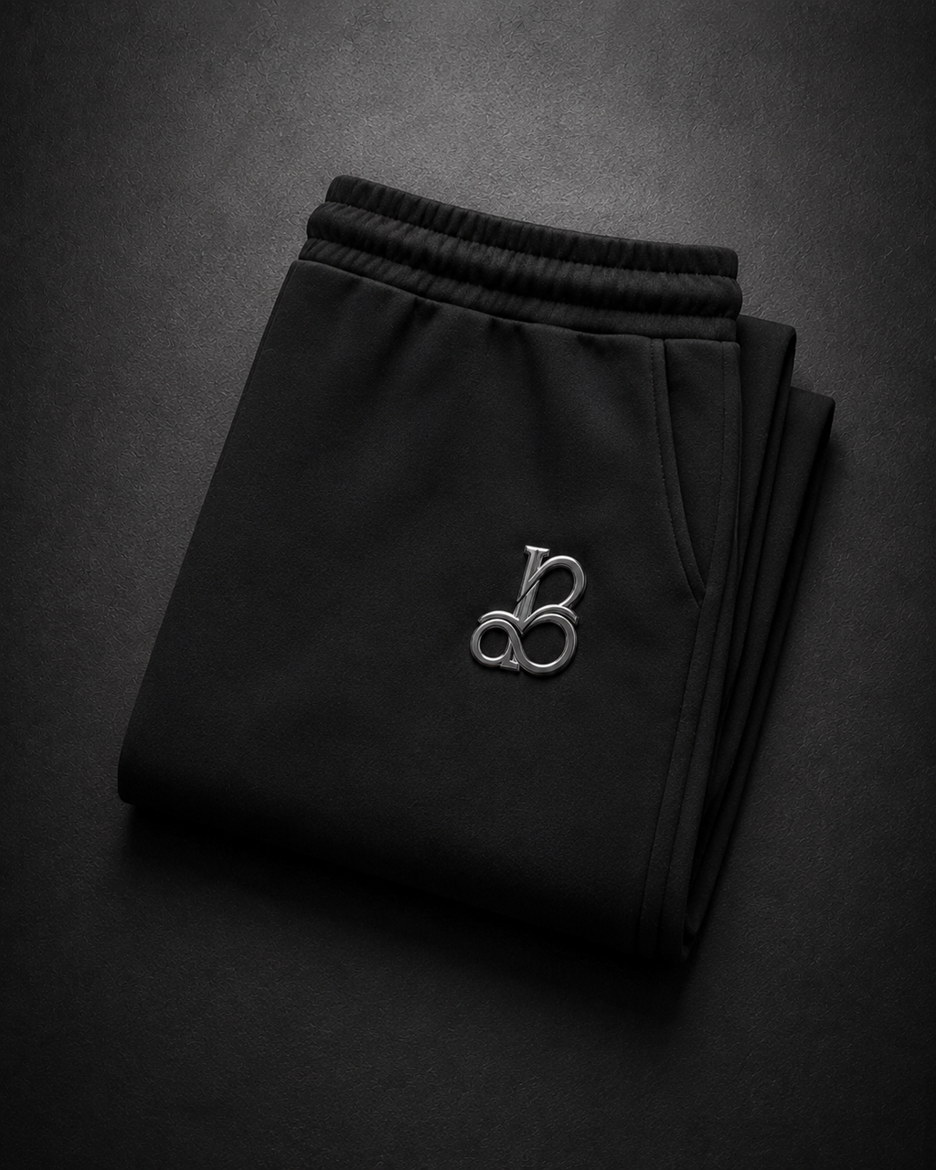 Folded black pants with a logo on a dark background