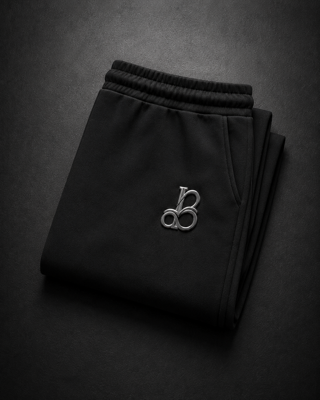 Folded black pants with a logo on a dark background